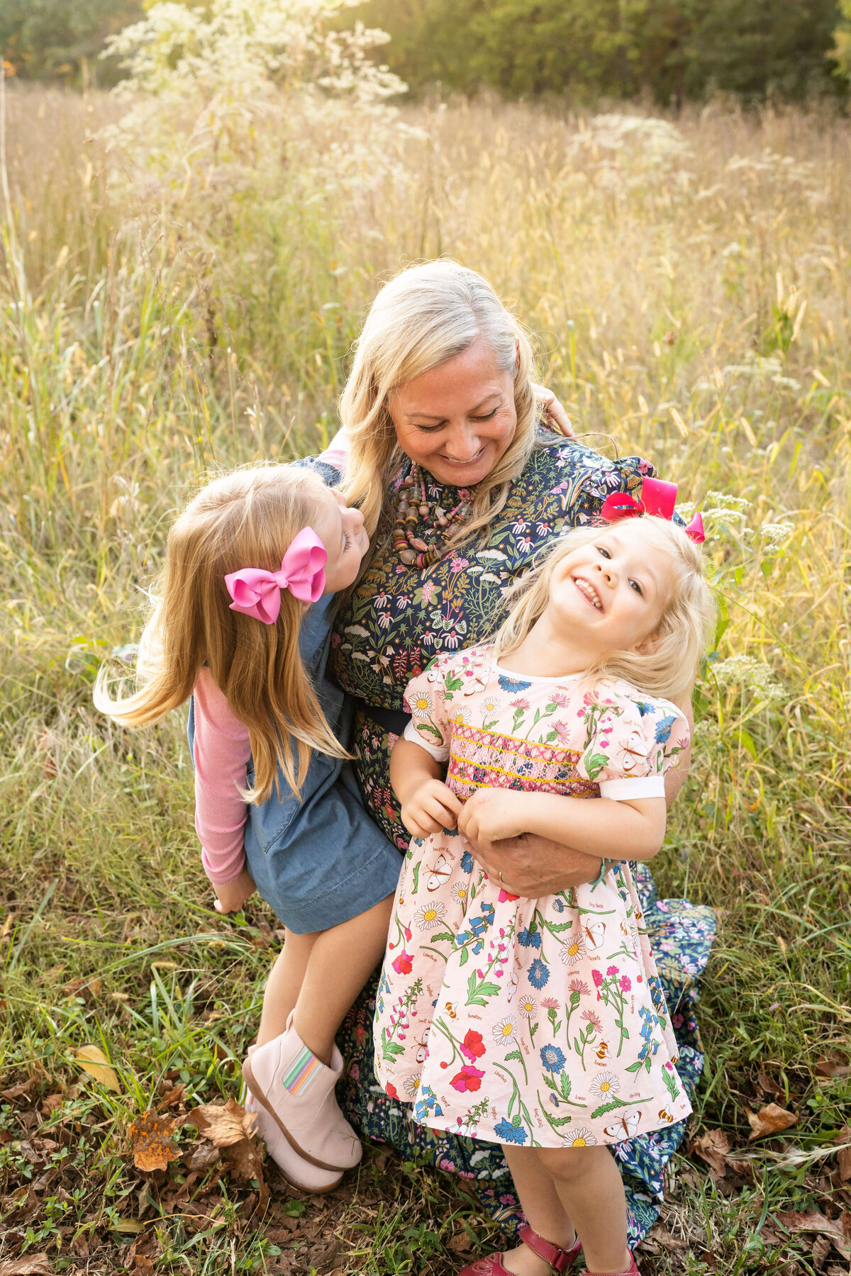 Mother laughing with daughters in tall grass by Atlanta family photographer