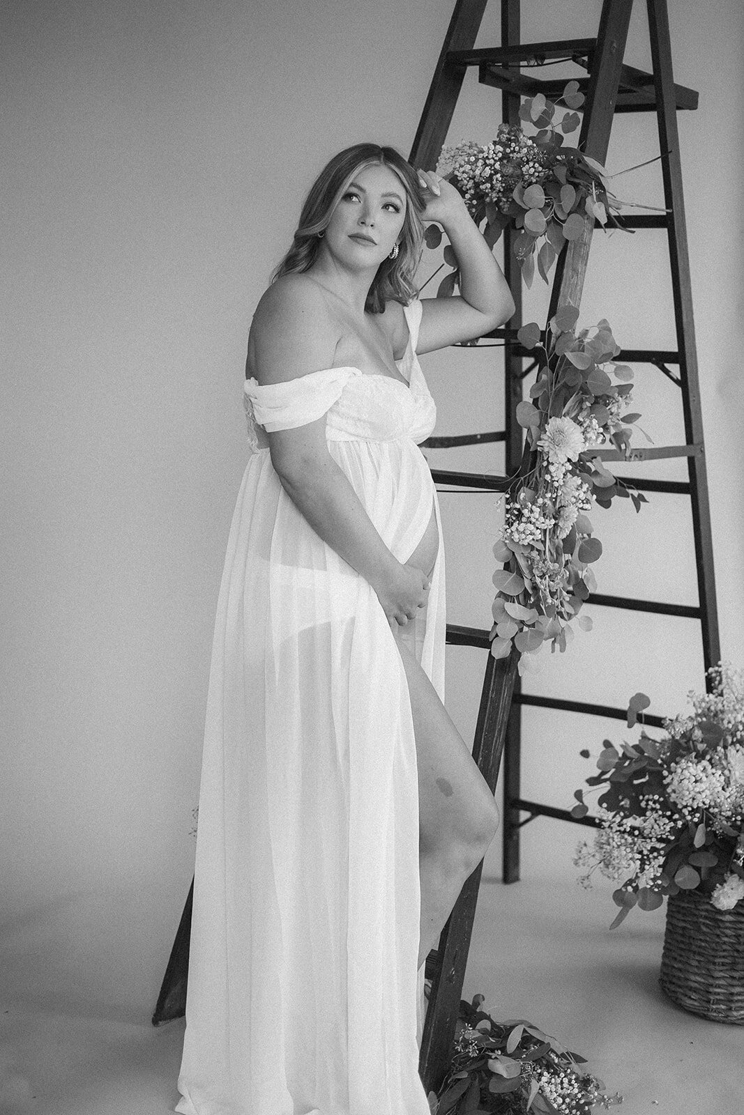 A woman looks into the distance leaning on a ladder