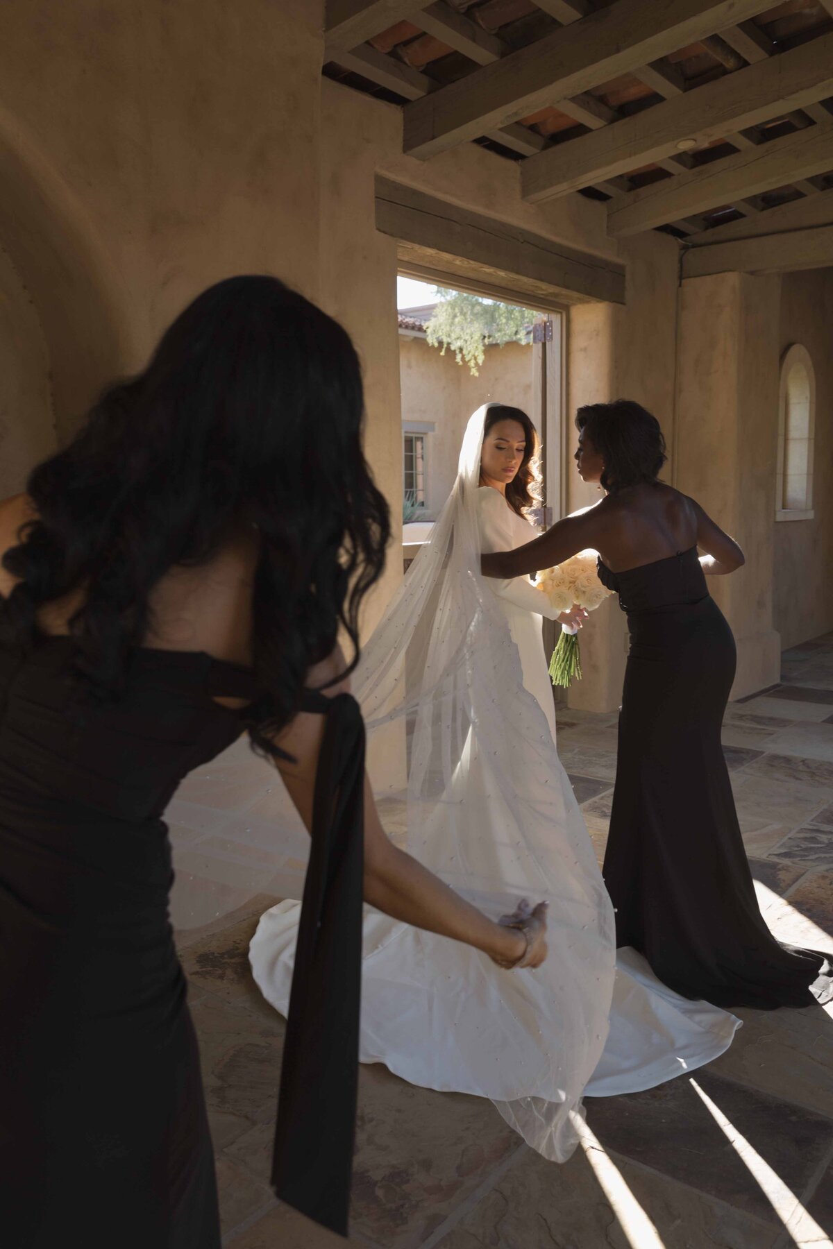 Photographers helping bride to pose in a white dress with a long veil