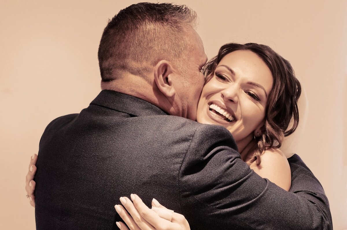 Bride smiling as she hugs her father