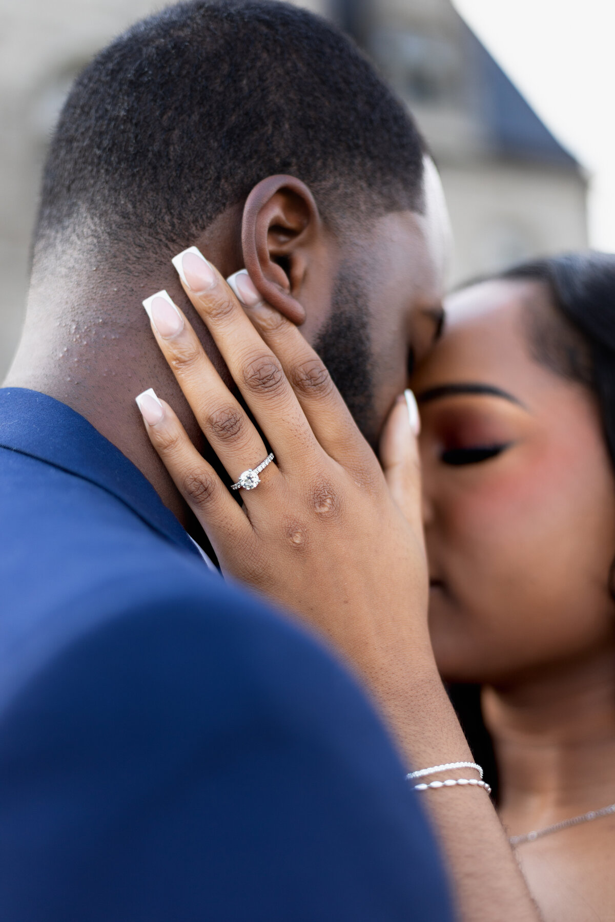 Engagement Photos Rhode Island | Kelsey Sheehan Photography Timeless Rhode Island Weddings | A couple shares a tender kiss, with a focus on the woman's hand resting on the man's face. She wears a diamond engagement ring, conveying love and commitment.