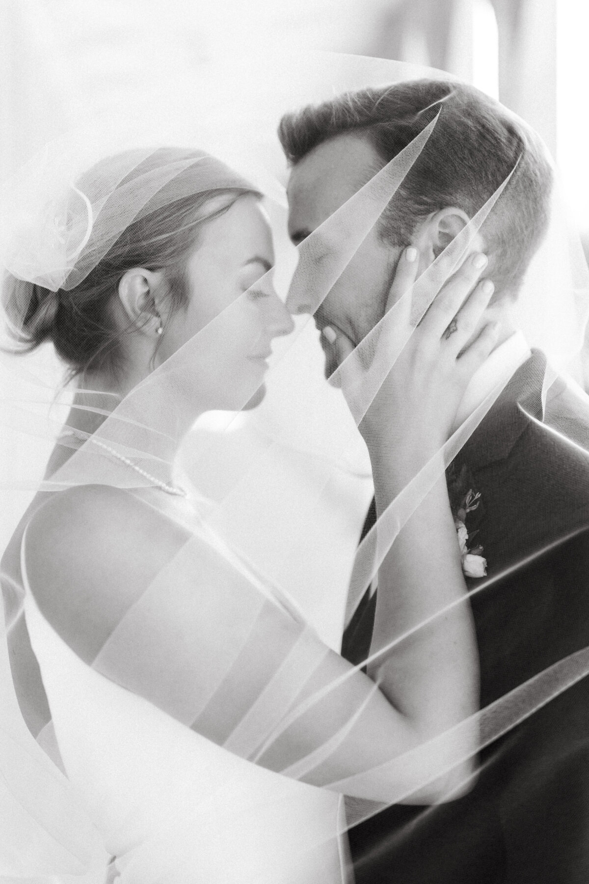 Bride and groom share romantic moment under flowing veil