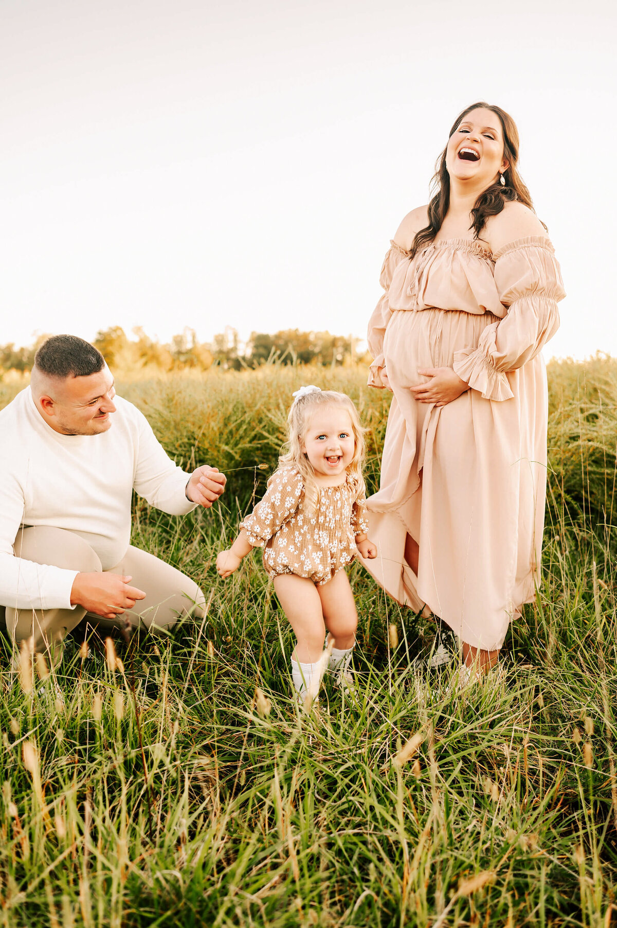 pregnant mom laughing with family outdoors during Joplin MO maternity photography session
