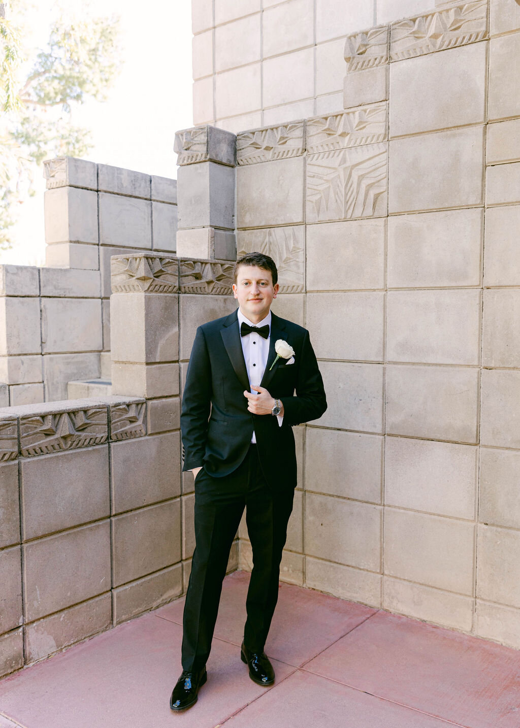 Groom portrait in classic black tuxedo against Arizona Biltmore architecture.