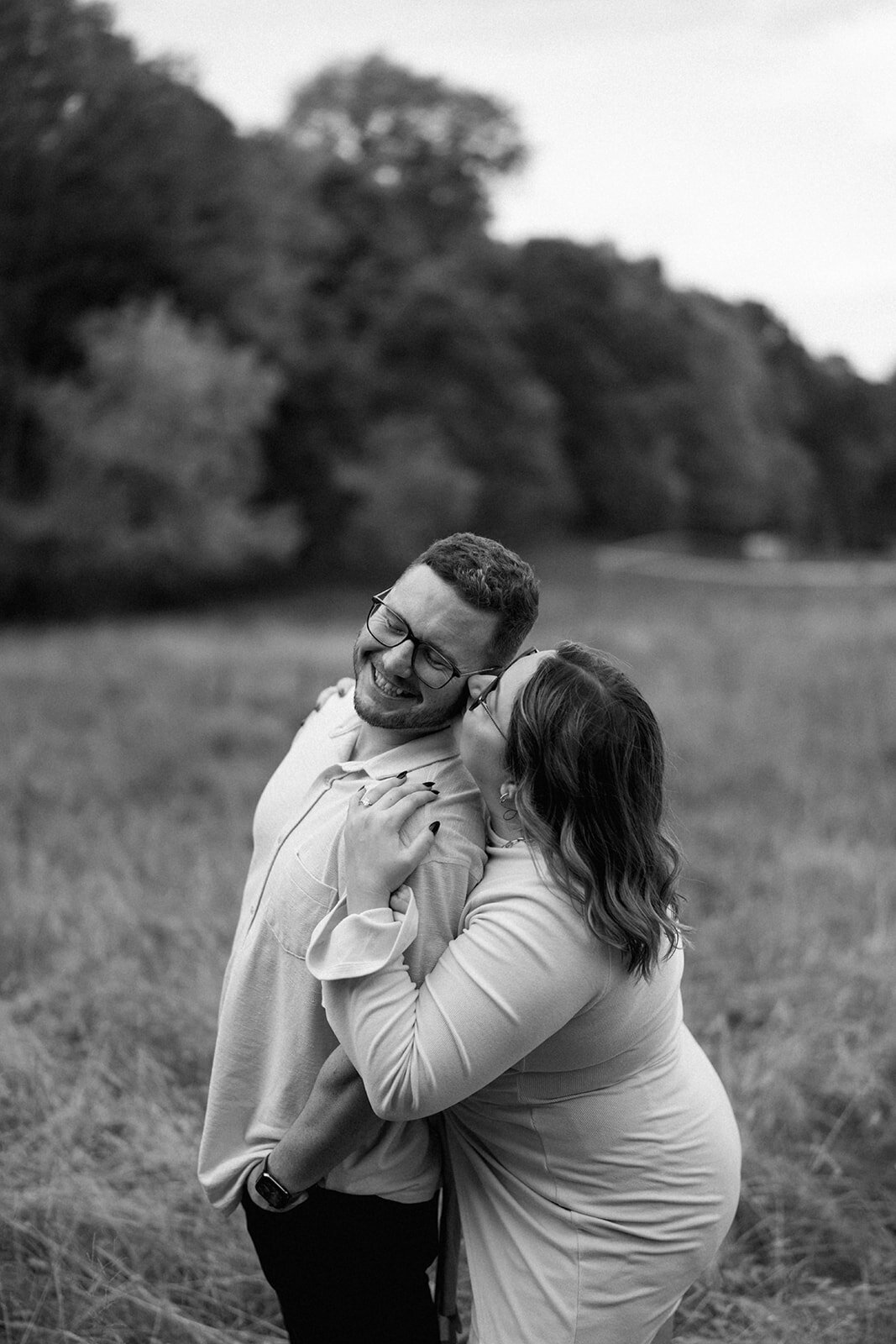 Black and white photo of the couple embracing and smiling during their engagement session at Al Sabo Preserve in Kalamazoo.