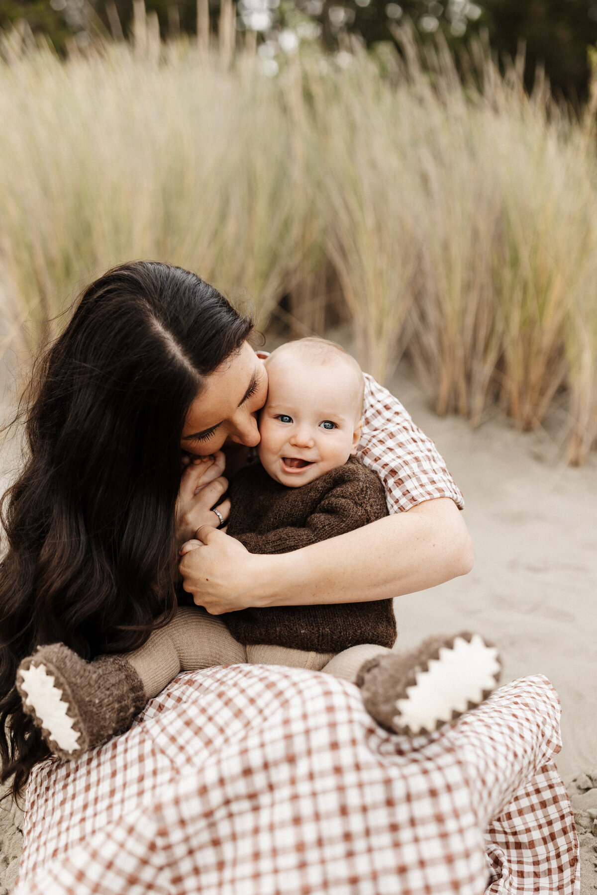 Sarah hugs her little baby boy during a family photoshoot at the beach near christchurch
