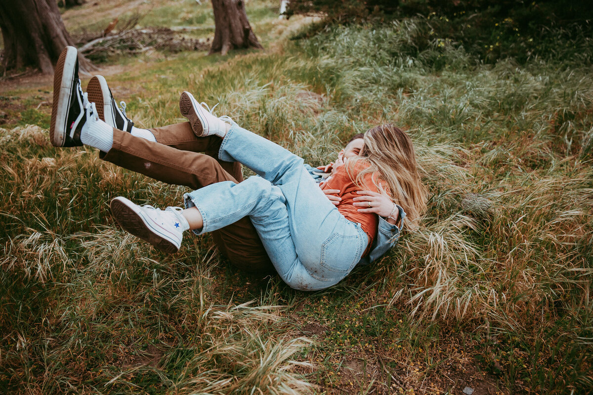couple-falling-into-grass-laughing