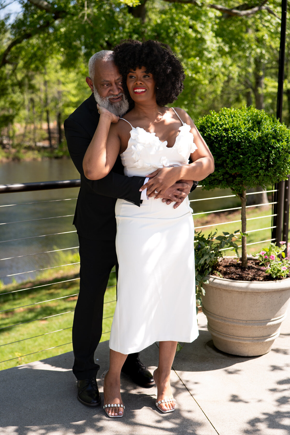 A person standing behind their partner with their arms wrapped around their waist
