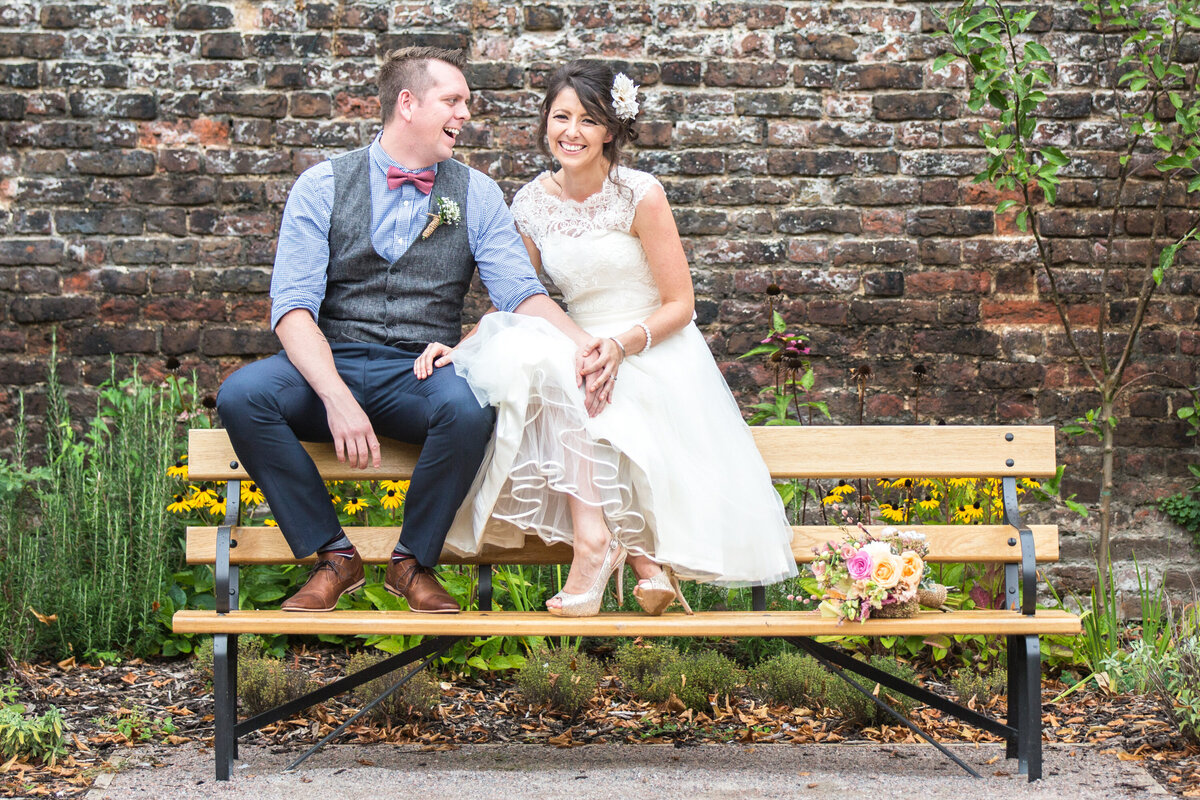 Bride and groom sitting together on park bench
