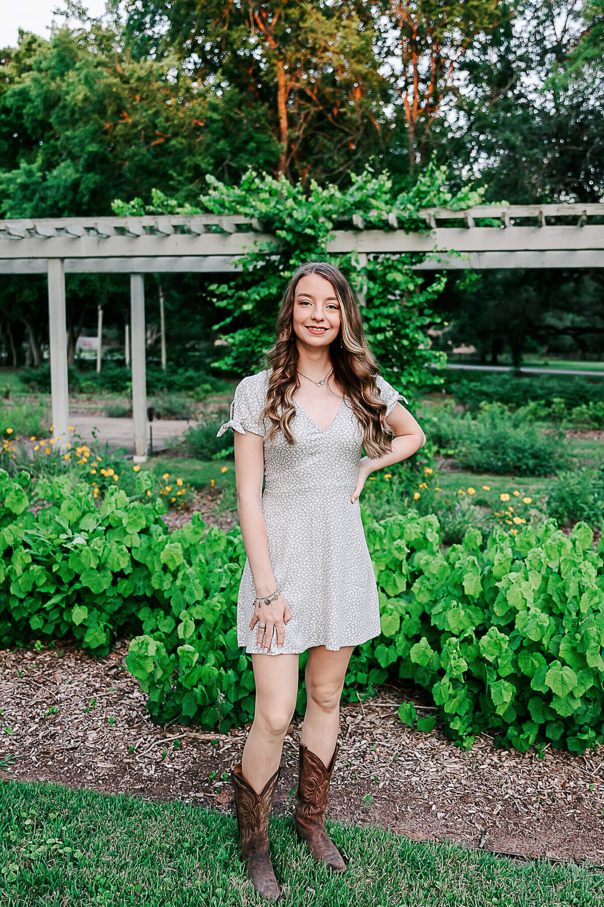 Senior in cowboy boots and dress in garden