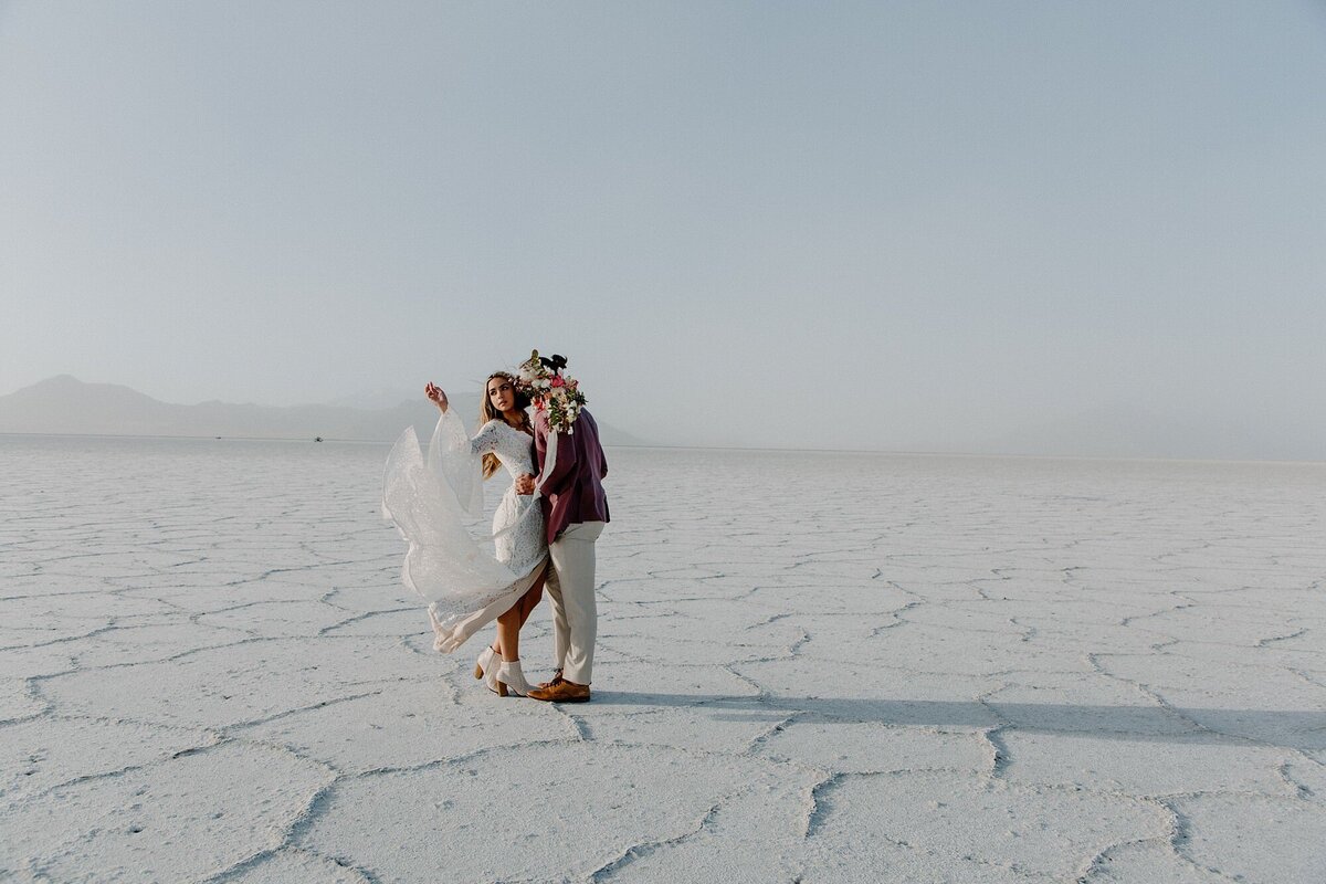 a couple on their elopement day embracing off in the distance on the utah salt flats