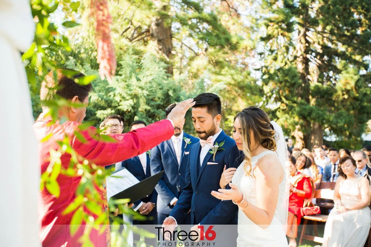 Bride and Groom being blessed by officiant during wedding ceremony