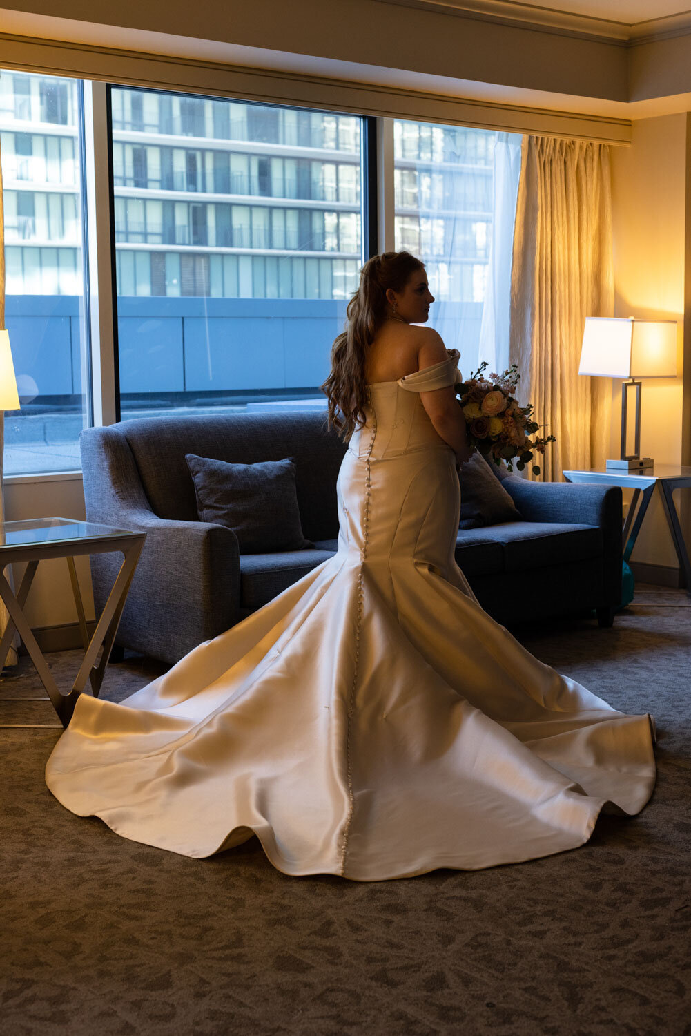 A woman in a wedding dress is standing in front of a couch