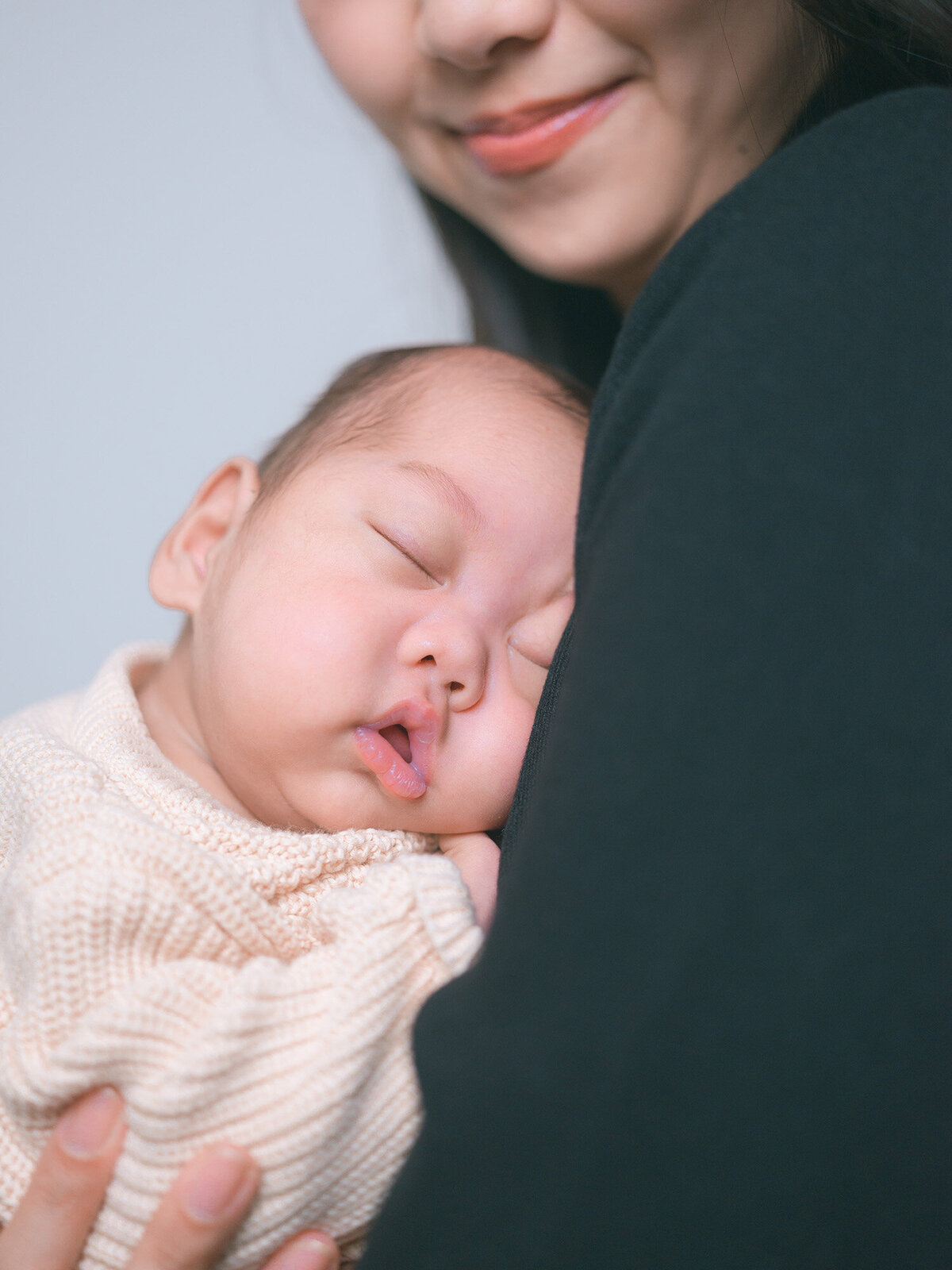 Newborn baby resting peacefully in a parent’s arms, photographed by an expert Menlo Park newborn photographer.