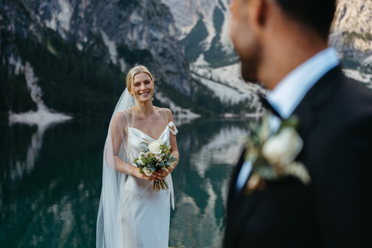 Bride and groom looking at each other on lakeside dock