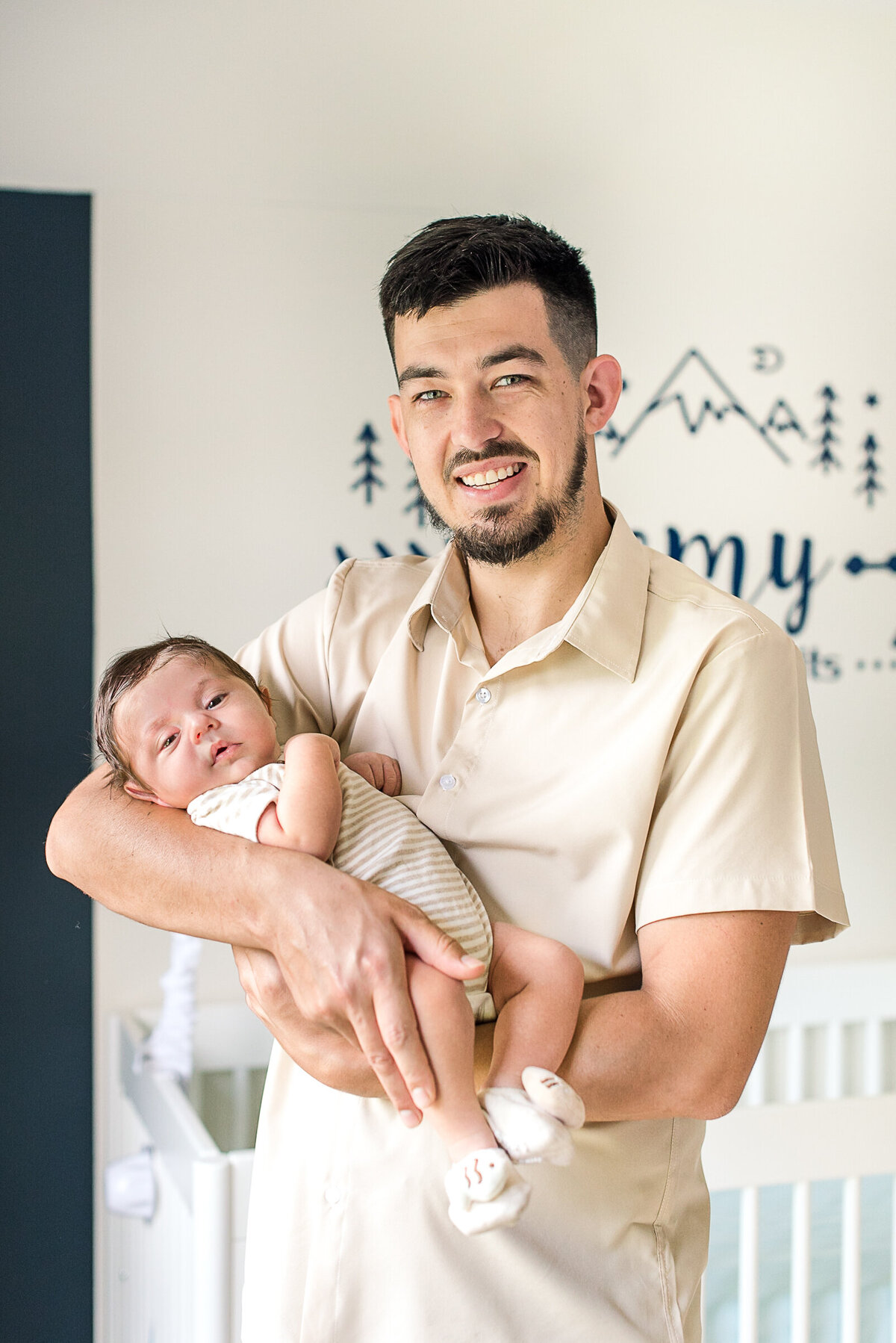 dad holding baby boy in neutral outfits in nursery