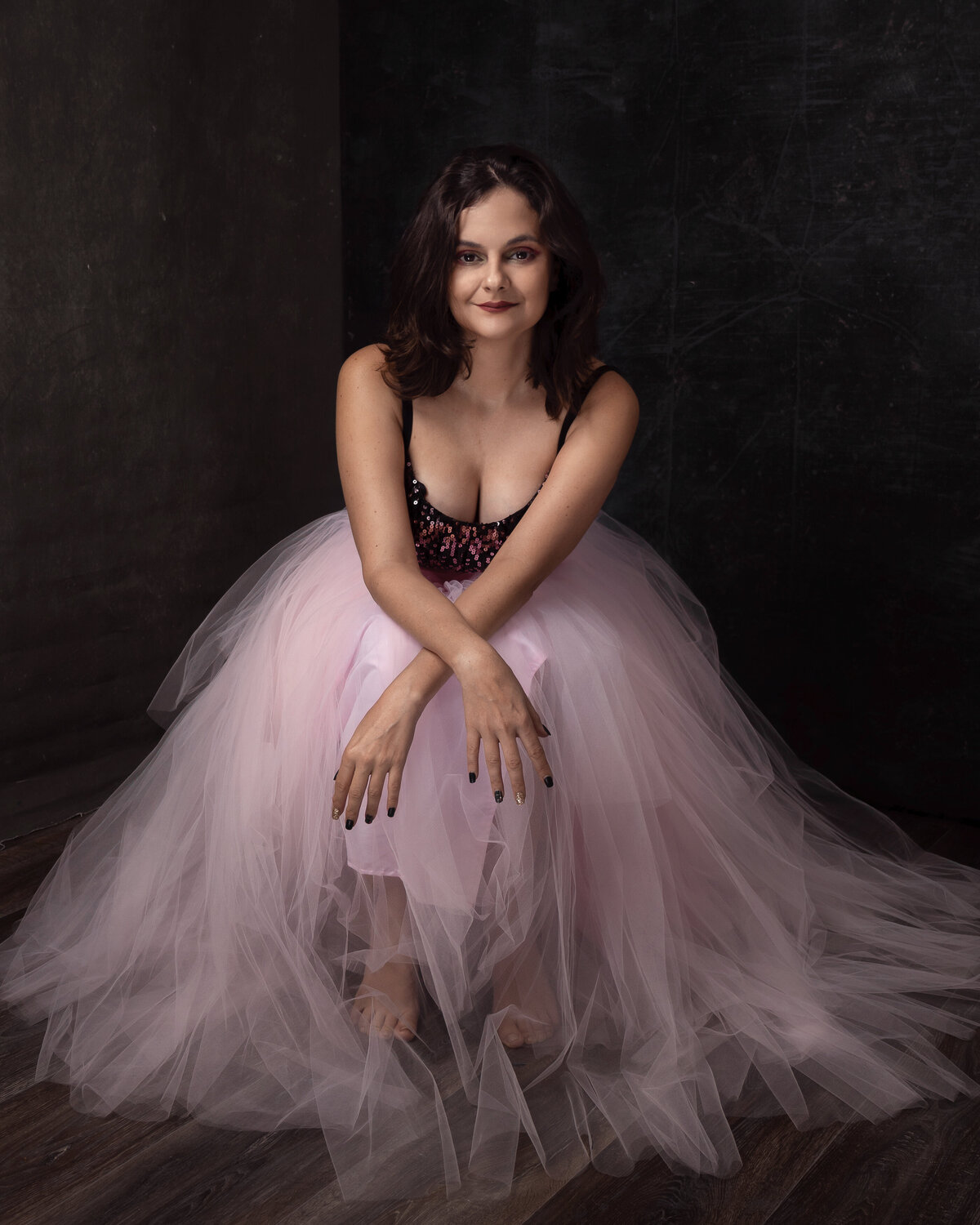 woman in pink flowing tulle sitting with crossed hands leaning forward