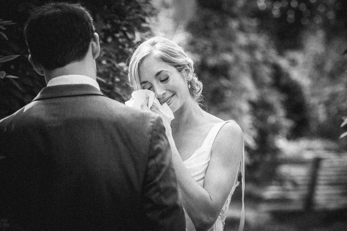 A bride wiping away tears as she stands with her groom.