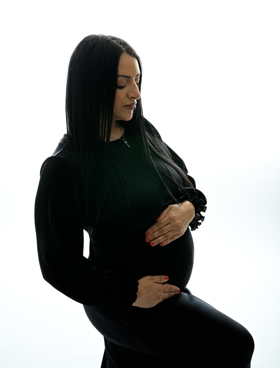 High key lighting studio maternity session with momma wearing modest black dress