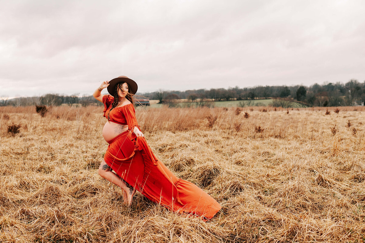 pregnant mom with wind blowing her hair in field during Springfield MO maternity photography session