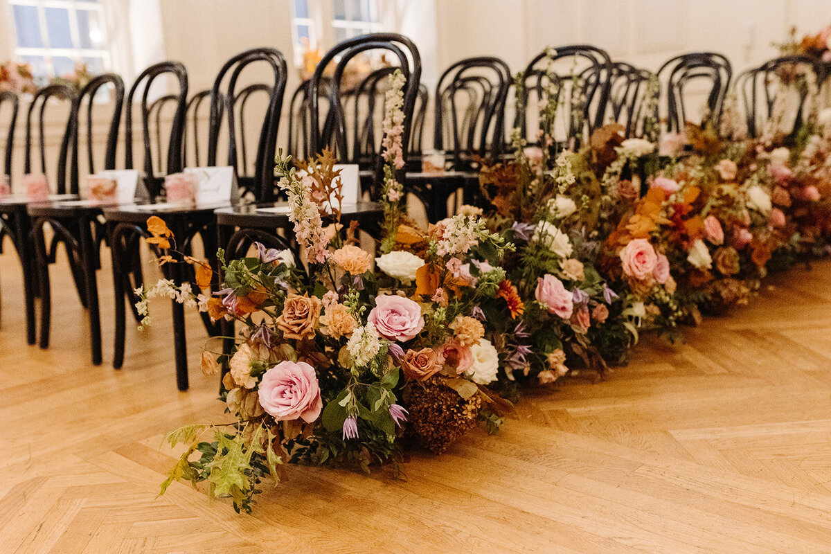Lush aisle hedges line the entryway for this autumnal wedding with florals composed of roses, clematis, mums, delphinium, copper beech, and fall foliage creating hues of burgundy, dusty rose, copper, mauve, taupe, and lavender. Design by Rosemary and Finch in Nashville, TN.