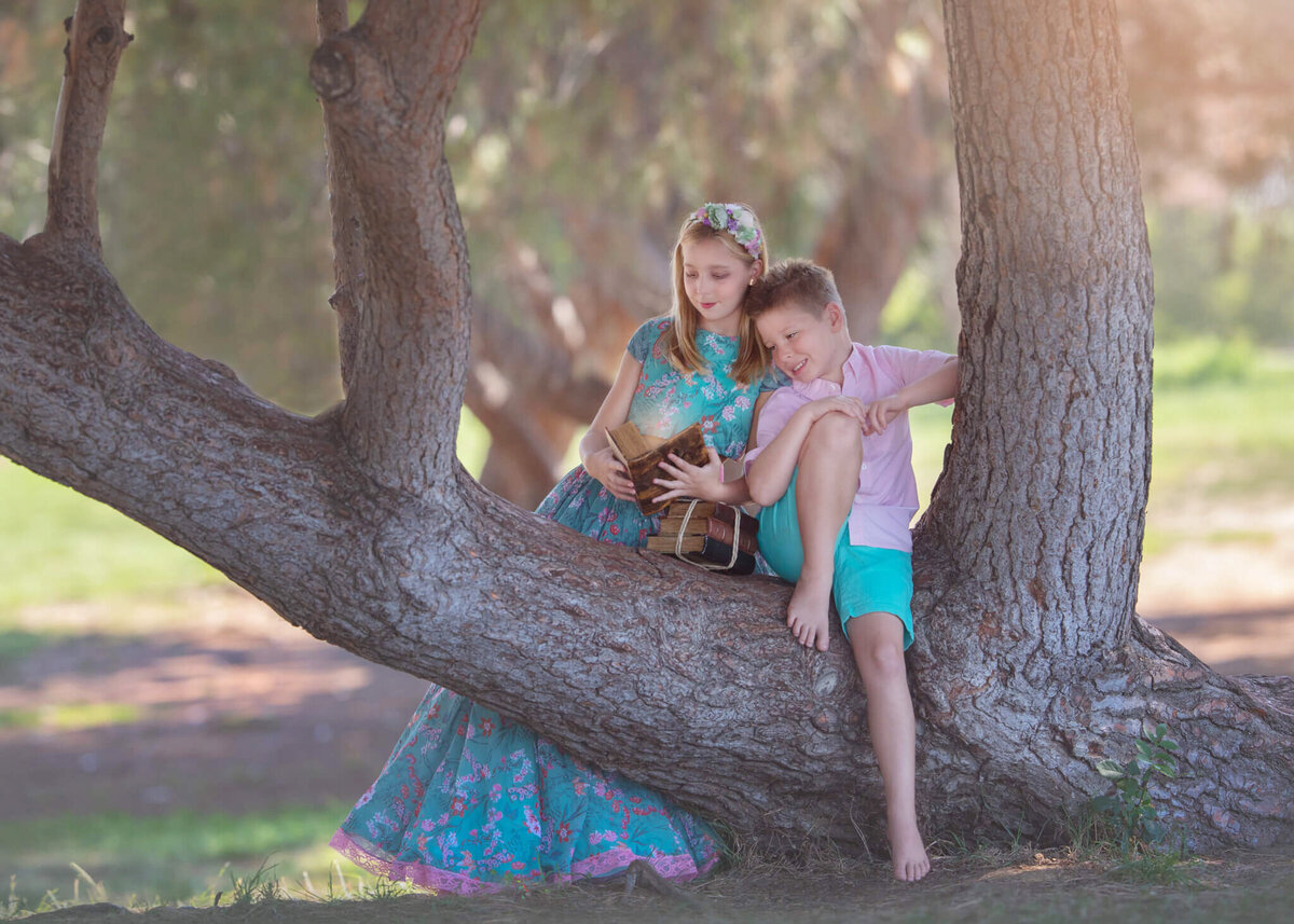 Brother and sister sitting in a tree reading a book at Lake Balboa Park