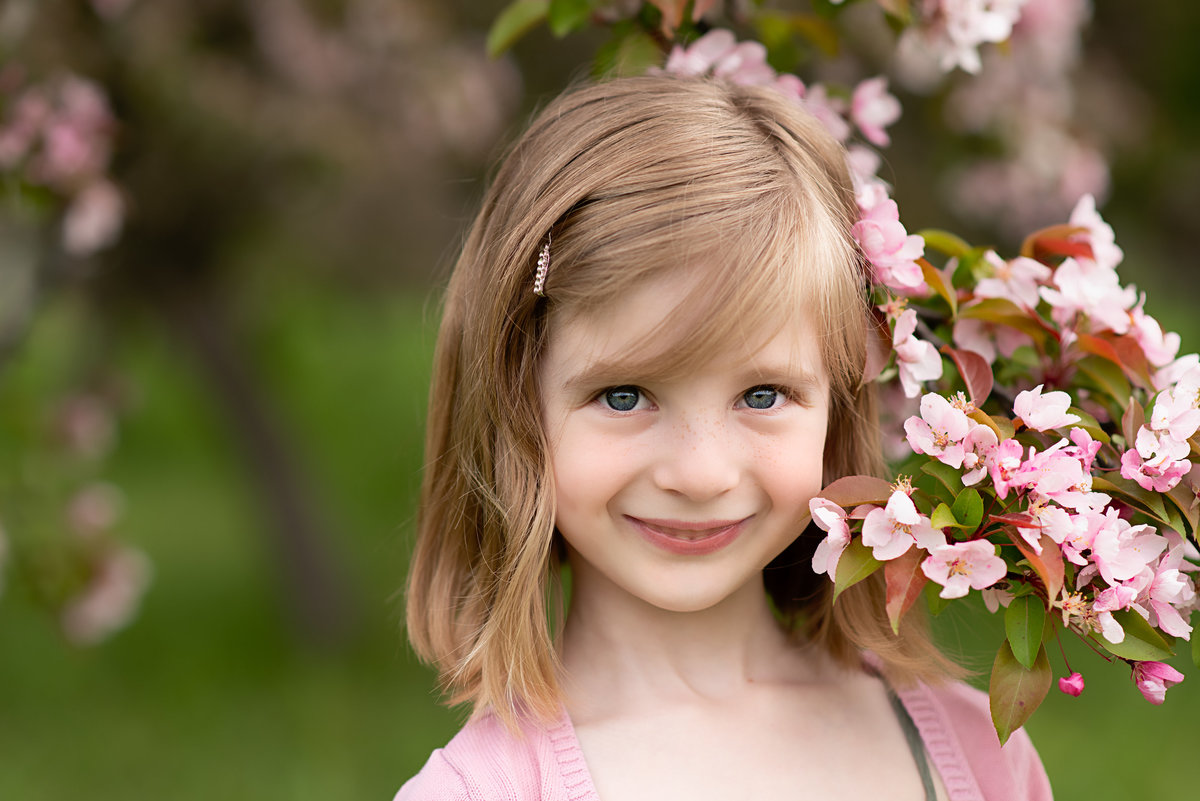 Girl looking into the camera surrounded by cherry blossoms.