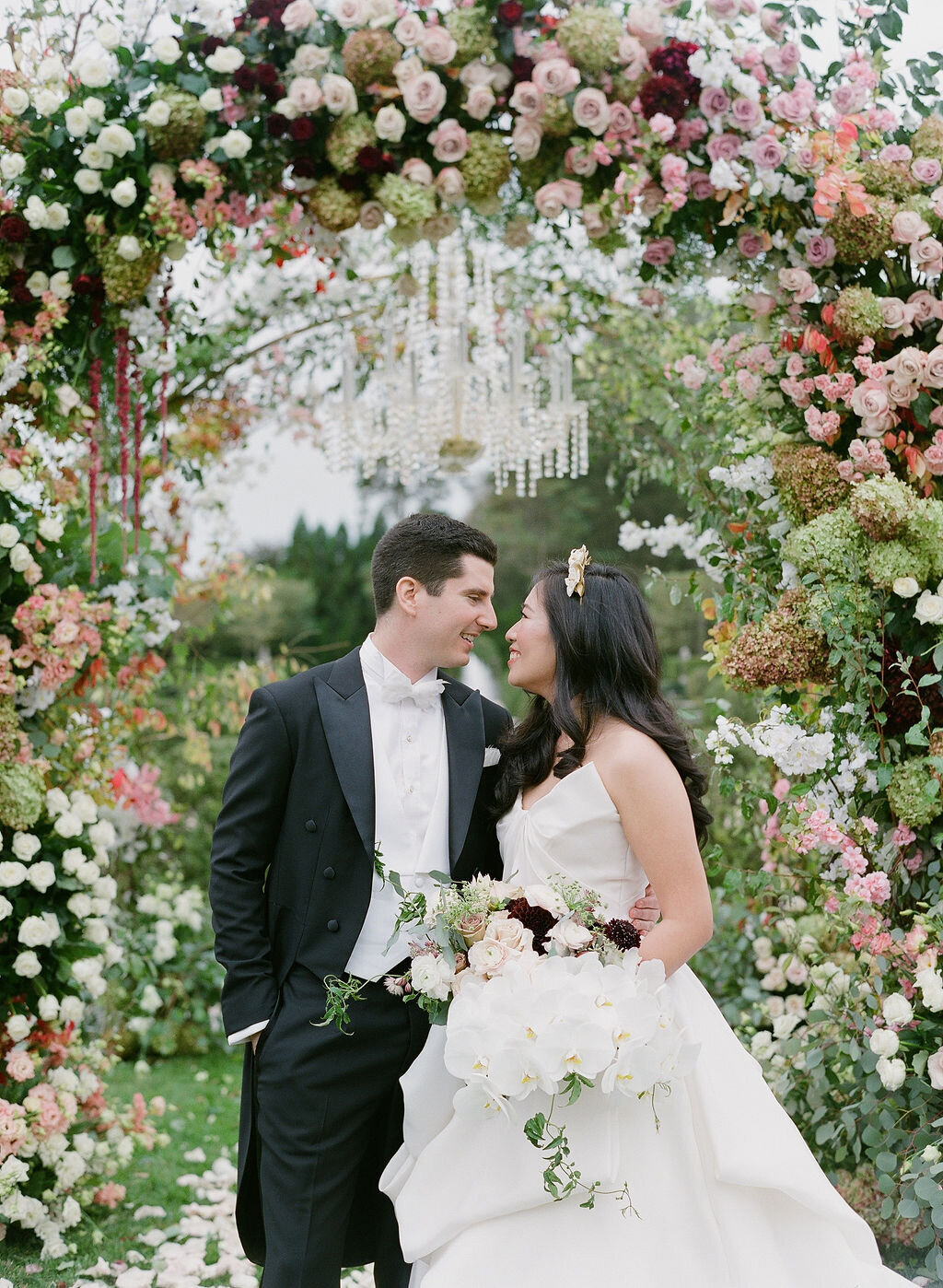 Bride and groom under lush floral arch at Oheka Castle Long Island Luxury Wedding