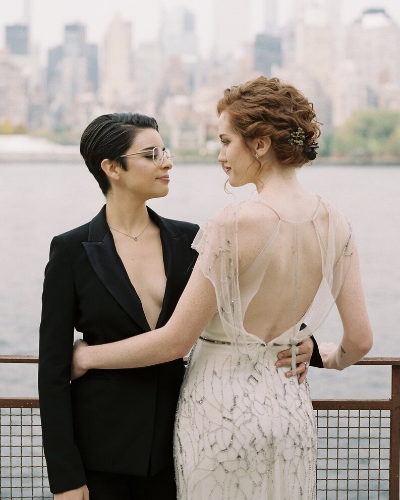 Two brides in front of the East River in Queens New York embracing