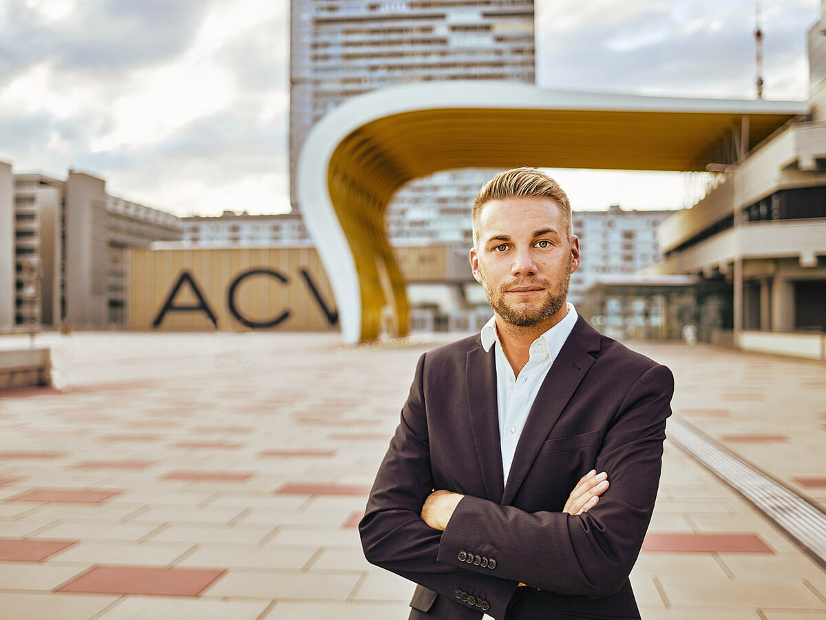 Selbstbewusstes Businessportrait eines jungen Mannes vor dem Austria Center Vienna – aufgenommen von Atelier Schulte. Kombination aus Portrait- und Architekturfotografie für starke Markenbilder.