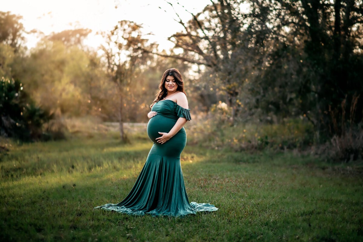 Pregnant woman wearing green maternity dress with husband on the beach
