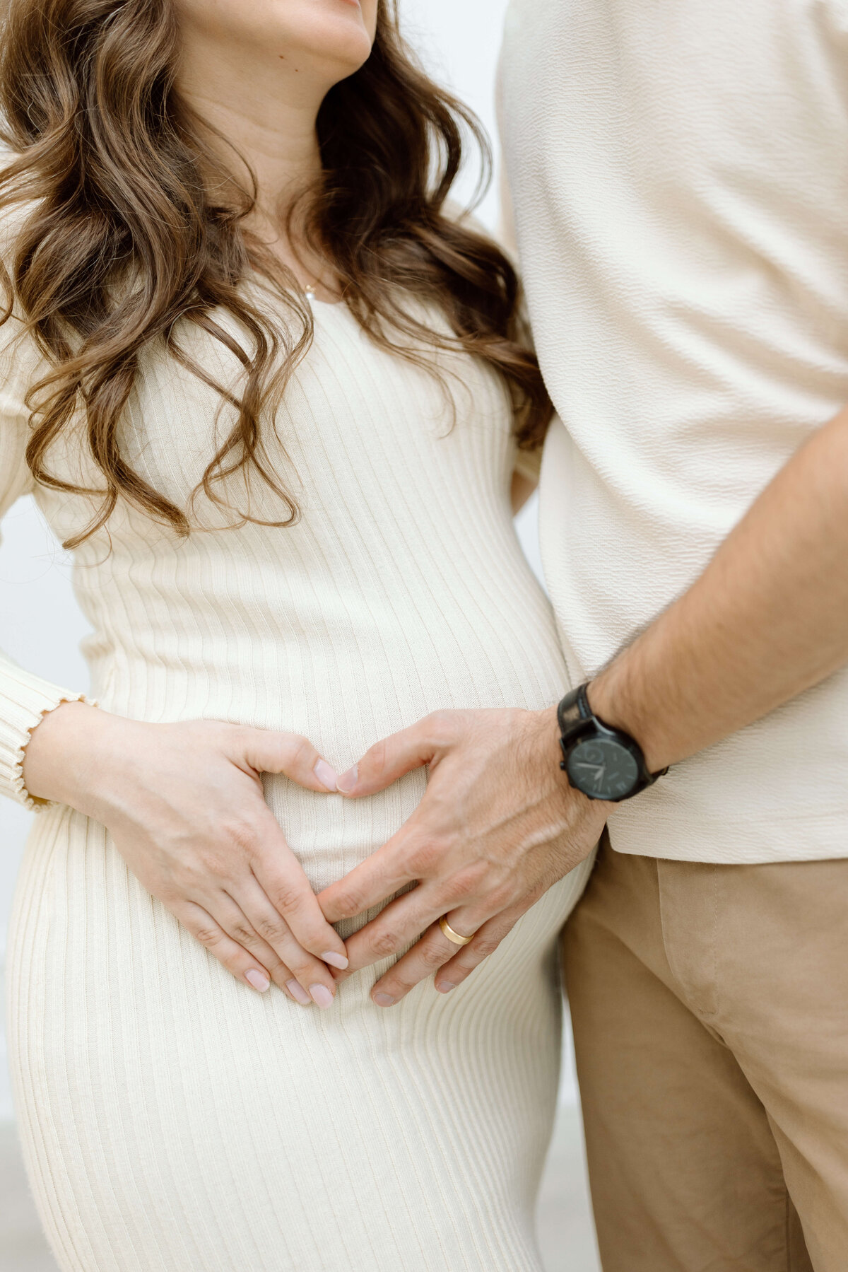 Expecting parents cradling a baby bump during their maternity photo session