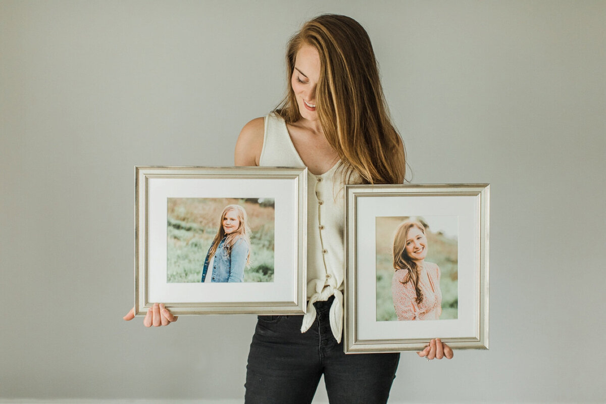 two framed family photos in silver frames are held by photographer