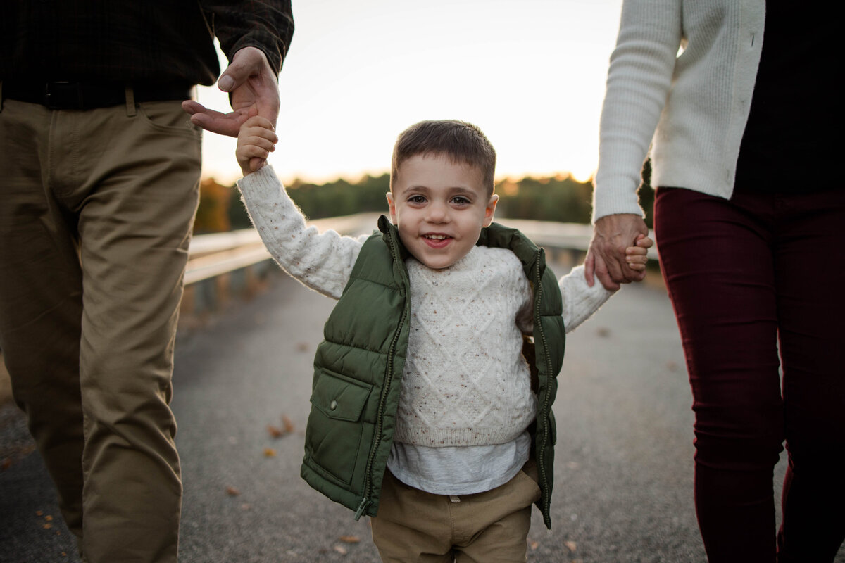 Toddler boy holding his parents hands