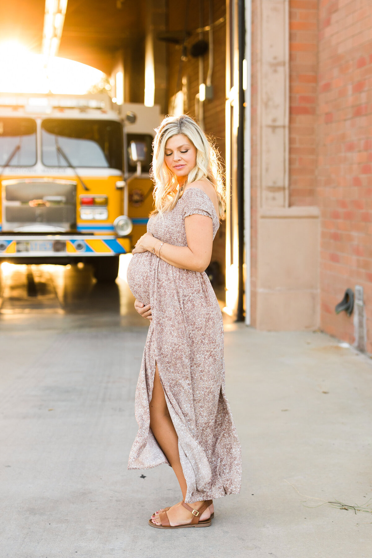 pregnant woman holding baby bump for maternity photography session at fire station