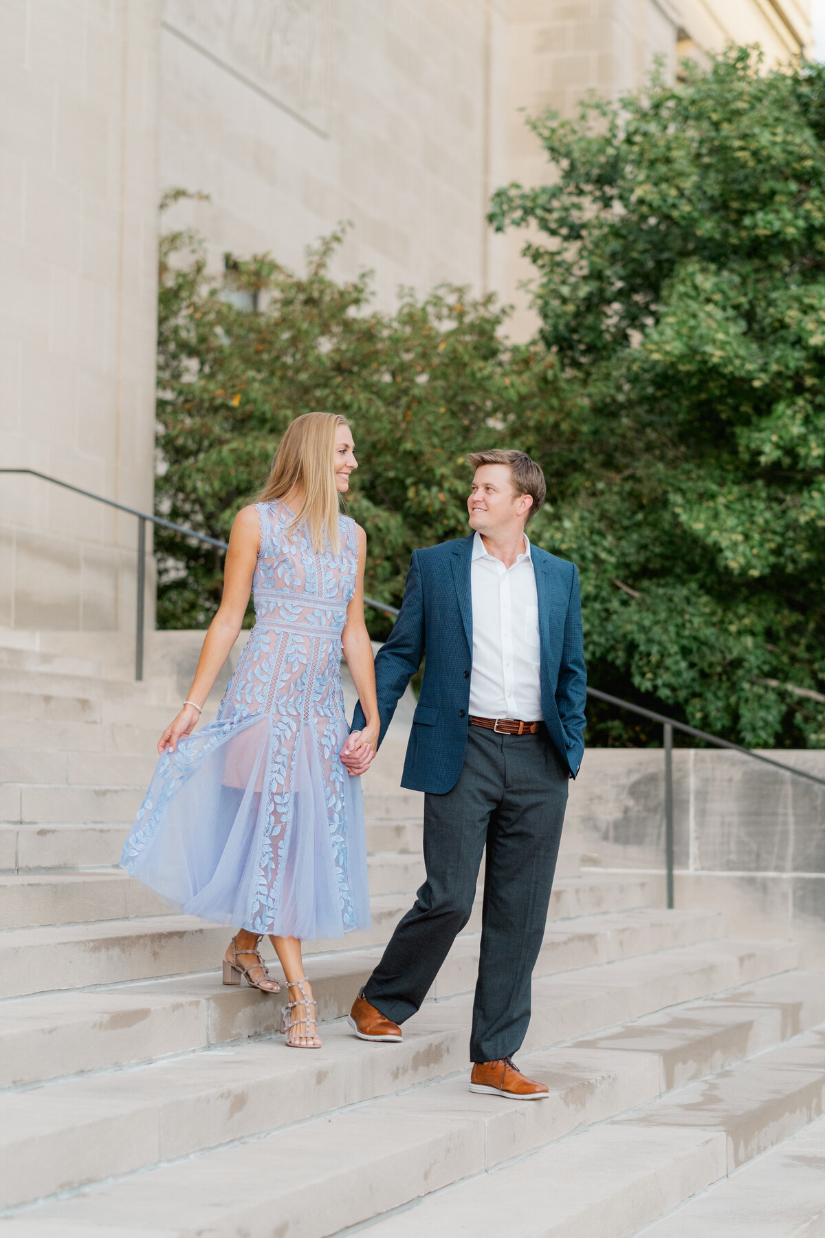 couple wearing blue blazer and purple dress walking down the stairs at the Nelson-Atkins Museum