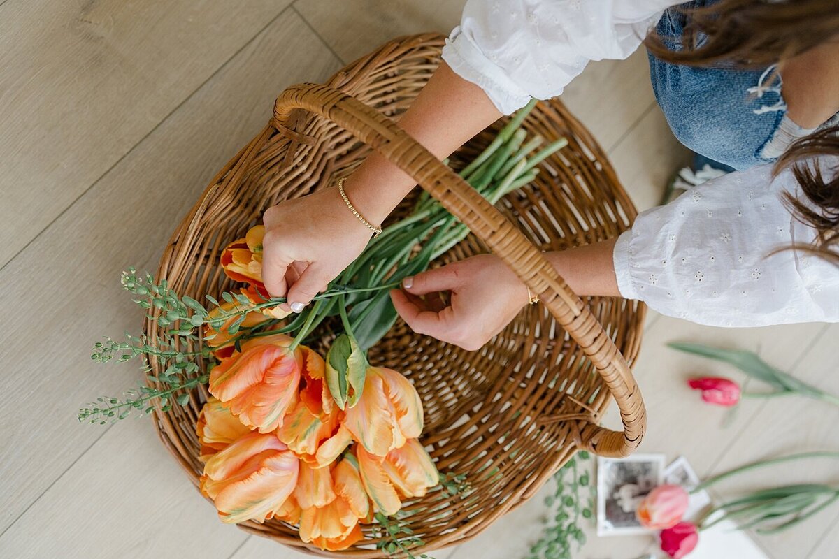 florist branding photos with woman arranging orange tulips in a rattan basket