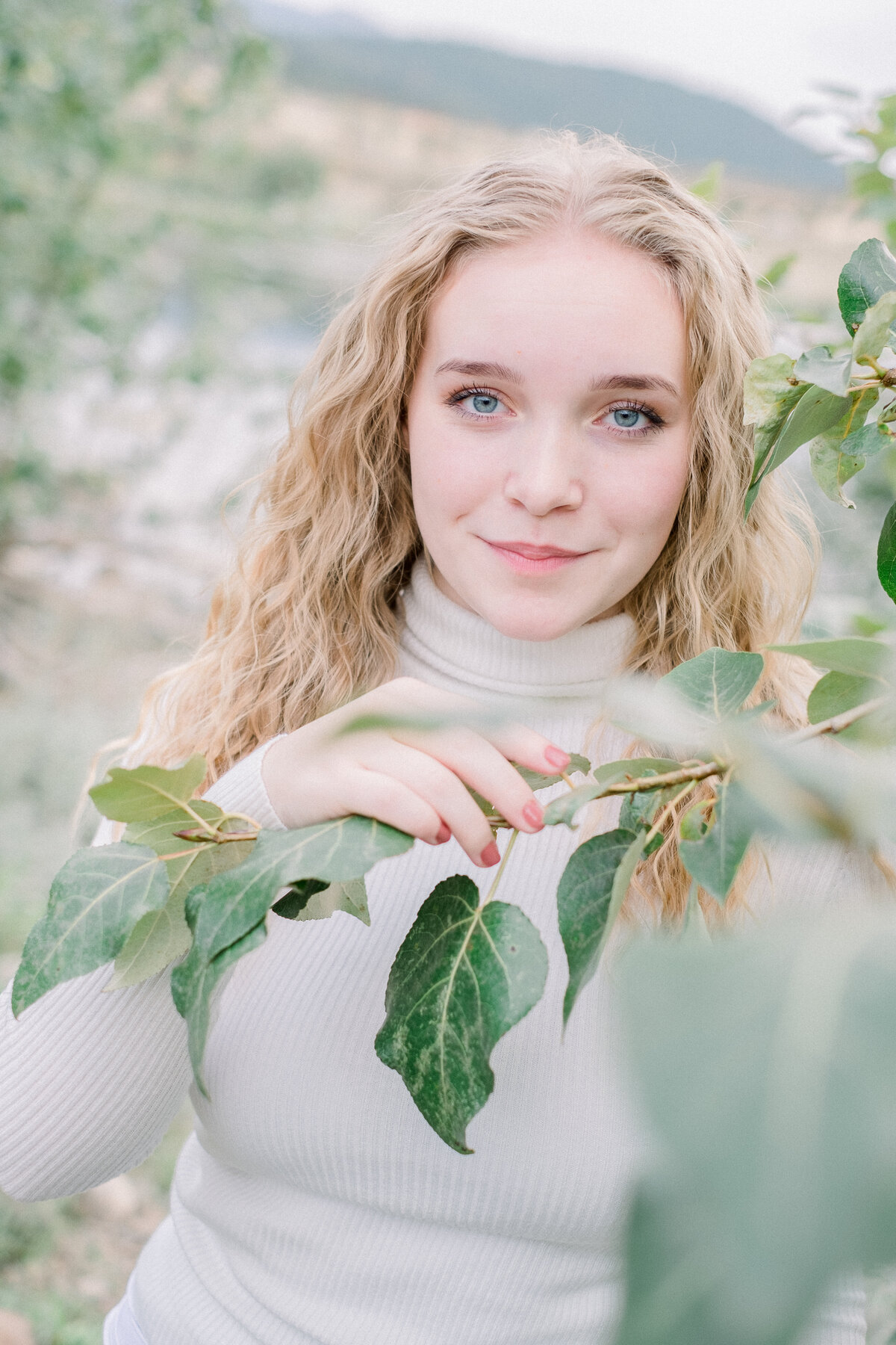 high school senior holding leaves while looking at the camera - taken by spokane senior photographer