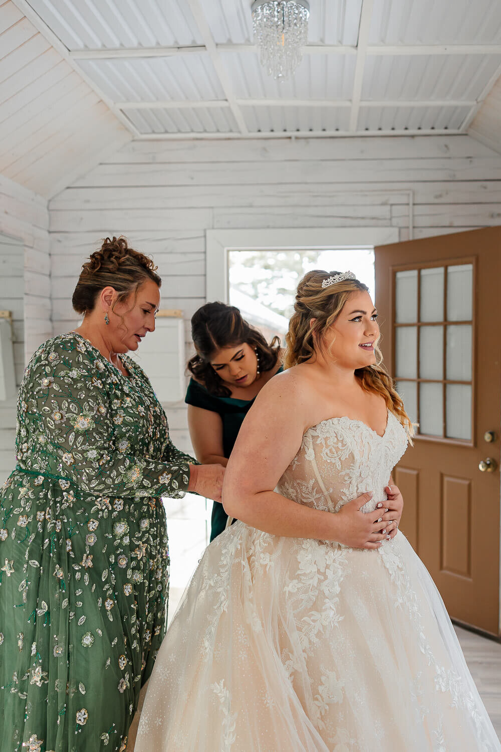 brides dress getting put on with her smiling.