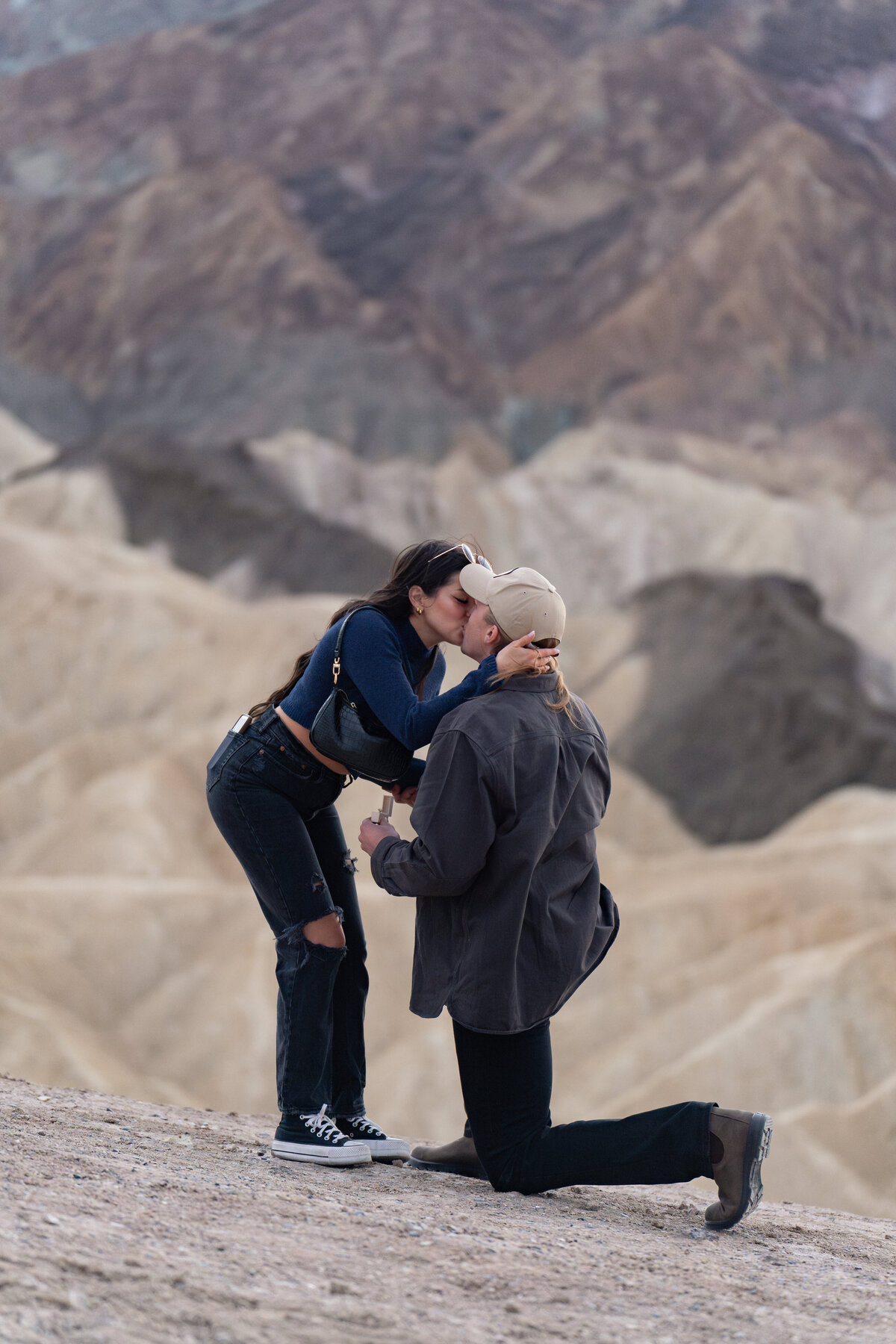 A person kissing their partner as they are kneeling down proposing
