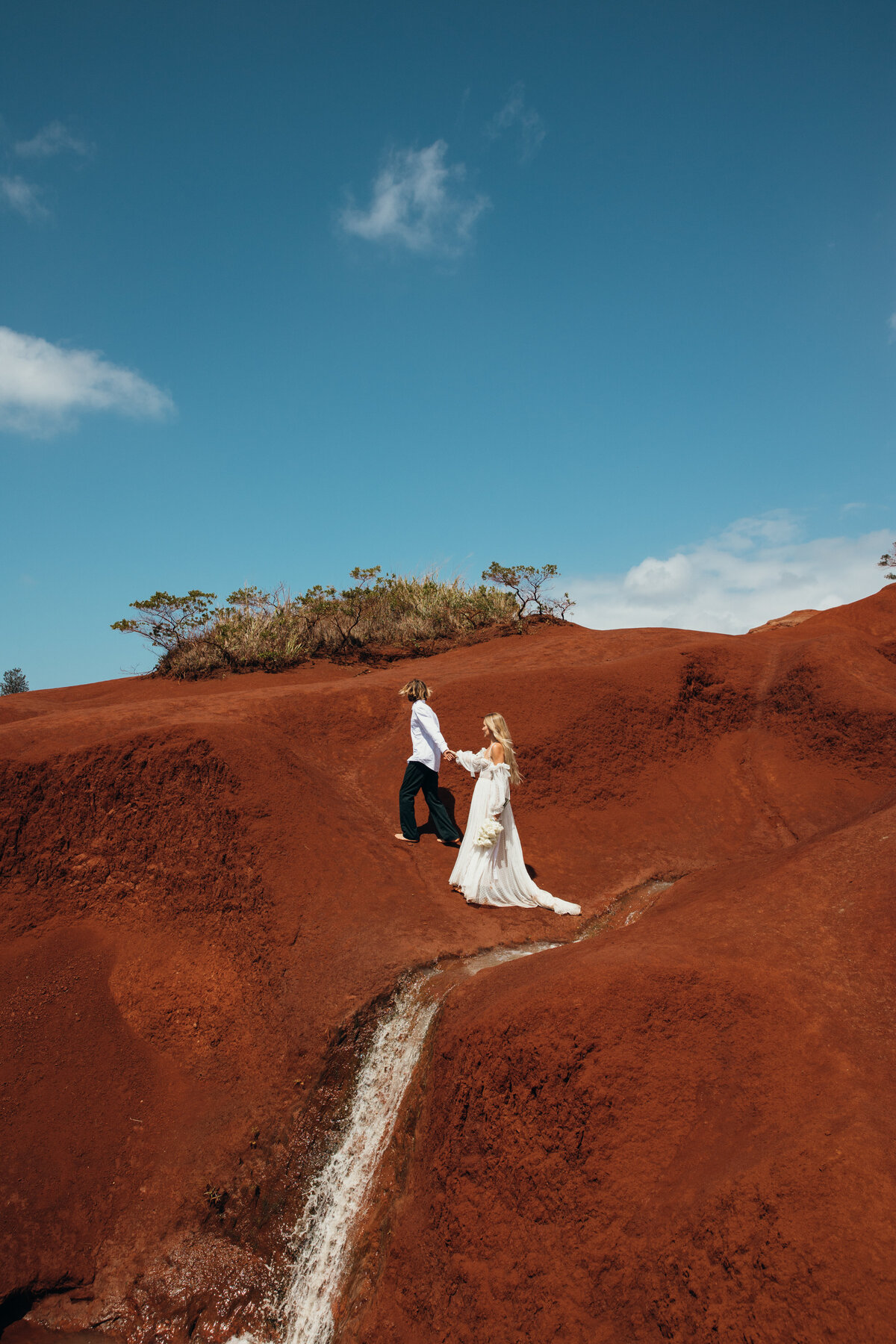 Maui Wedding Photographer captures groom leading bride on red sand beach