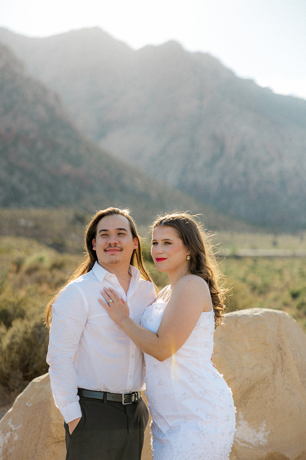 Engaged couples smiling with mountains in the background in Nevada