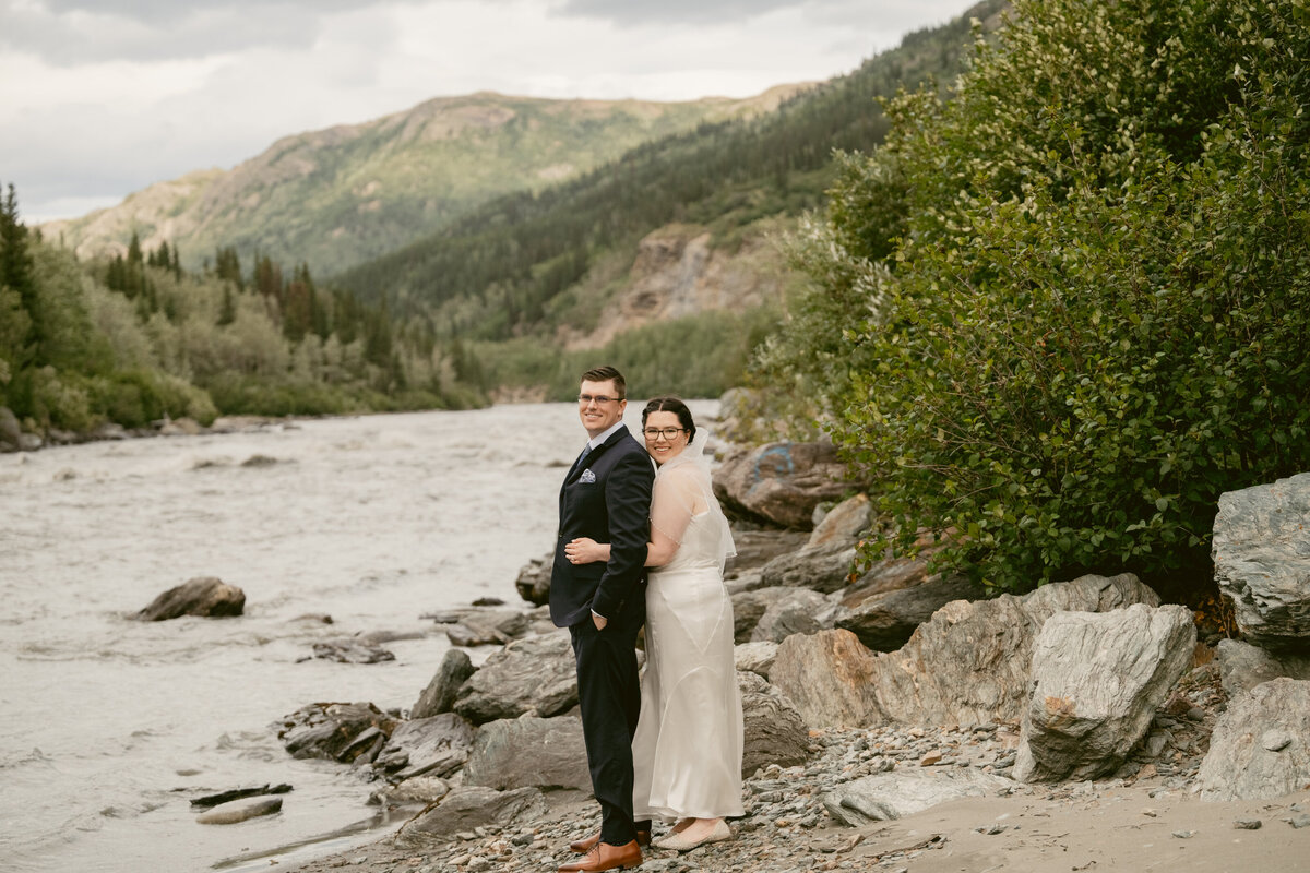 A newly married couple snuggles by a river in Denali Alaska
