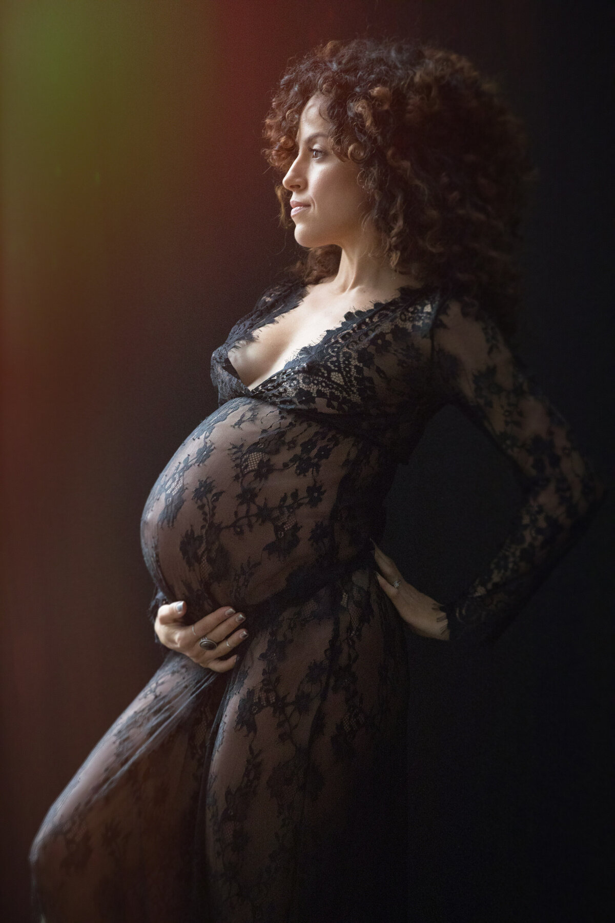 A pregnant woman holding her stomach with one hand while the other is on her back.
