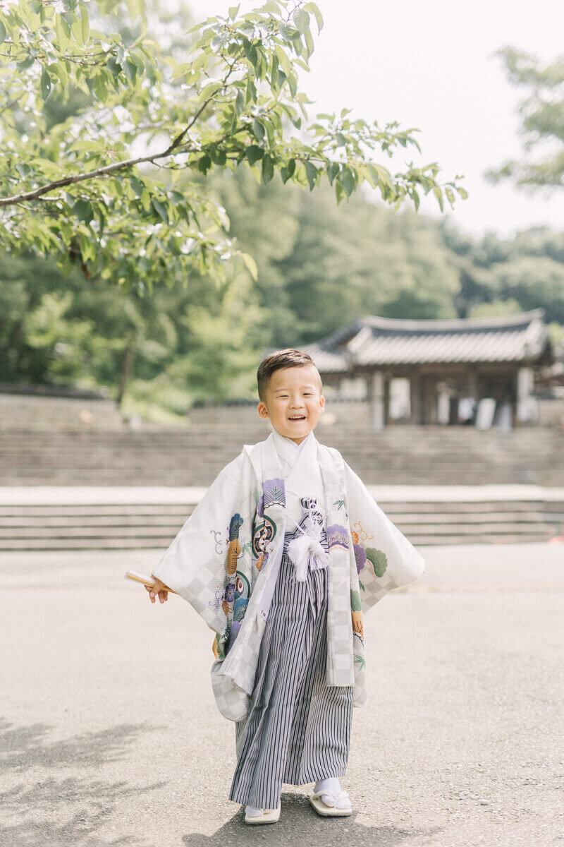 扇子を持って、袴姿で満面の笑みでポーズをきめる男の子の5歳の七五三写真。横浜市の公園での前撮り撮影はYukika Ishikawa Photographyが撮影。