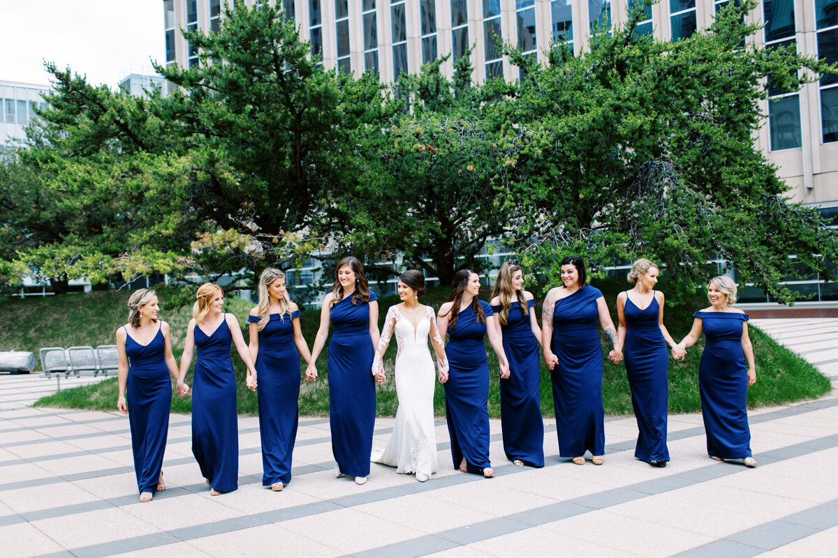 bride with her bridesmaids walking in Minneapolis holding hands