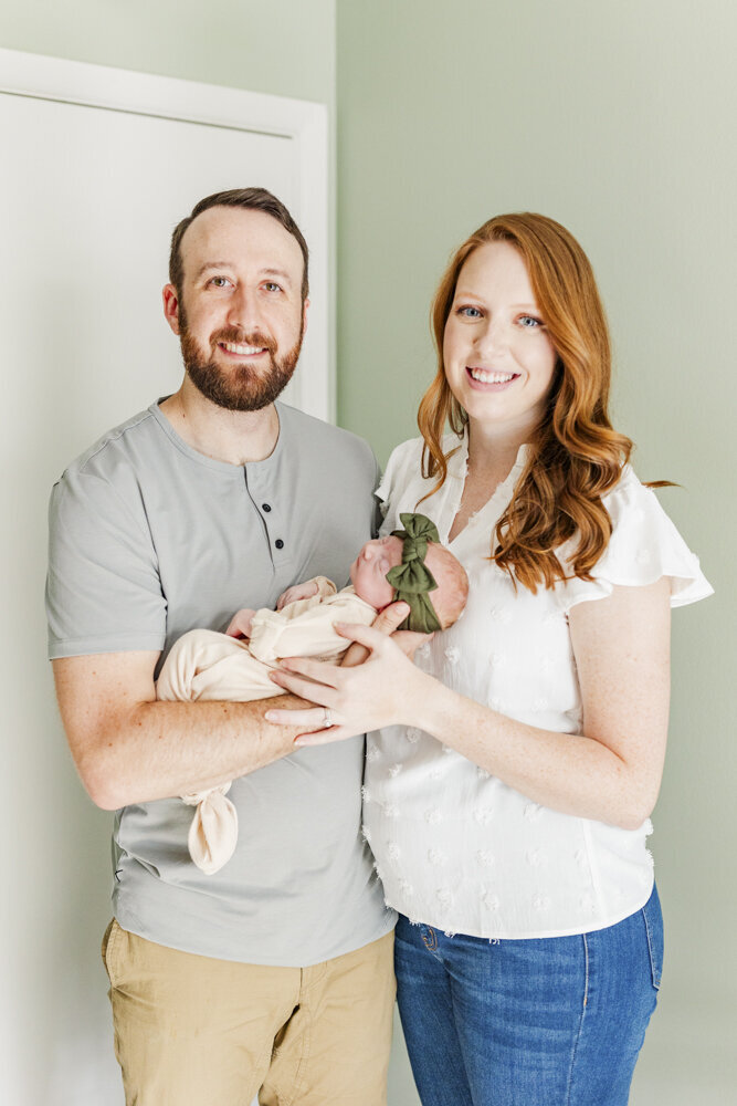 a man and woman smiling while holding their newborn baby