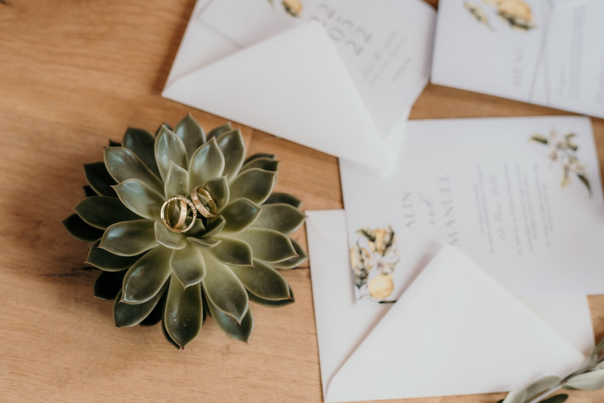 Some wedding invitations are draped on a wooden table.