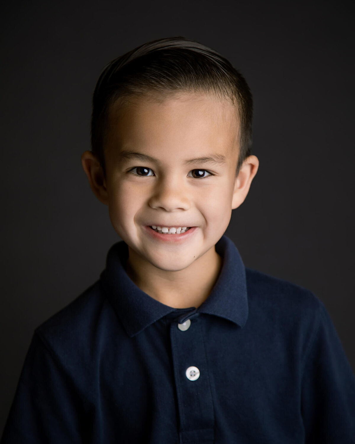 brown haired boy with a dark blue uniform shirt smiling for a school portrait