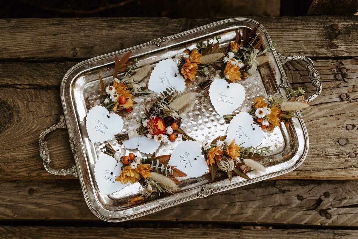 Personal flowers with name tags lay on a silver tray.